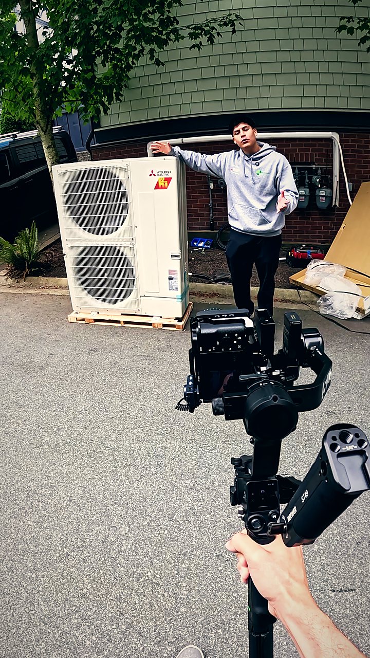 Filming an HVAC technician beside a heat pump install